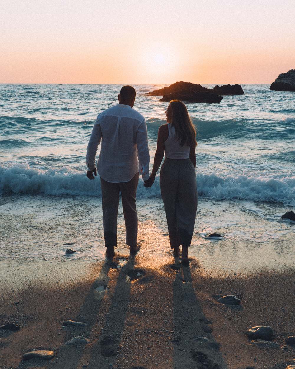Couple dressed in white laughing on the beach in Lefkada